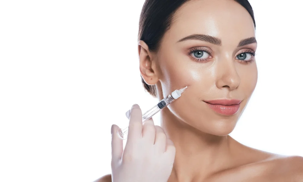 Headshot of a woman receiving dermal fillers in Linwood, NJ, with a gloved hand and syringe on a white background.